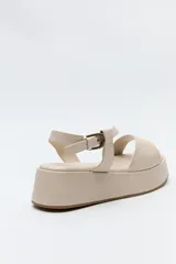 Sandalia marrón con plataforma, tiras cruzadas y pulsera ajustable.