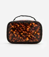 Neceser rectangular grande de plástico transparente con estampado de carey en tonos marrones. Tiene cierre de cremallera doble dorada, asa de mano negra y ribete negro.