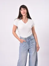 Remera blanca de punto con cuello en V y mangas cortas con volados.