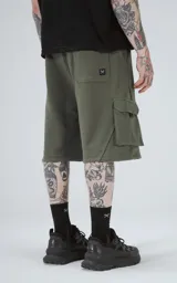 Bermuda de algodón rústico color verde militar, calce oversize, con elástico en la cintura y bolsillos cargo con cierre.