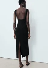 Vestido midi negro de corte ajustado, con cuello barco y espalda descubierta.