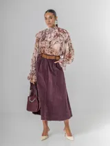 Falda midi de micro pana color morado oscuro, de corte recto y cintura elastizada. Incluye un cinturón desmontable de cuero marrón.