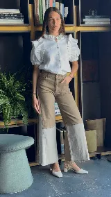 Jean wide leg de tiro alto, confeccionado en denim de algodón, con diseño bicolor en tonos de gris claro y gris oscuro/tostado. Presenta un efecto de parcheo vertical y terminación desflecada en el ruedo.