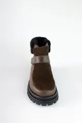 Bota corta de cuero color marrón con puntera y empeine de gamuza color beige. Tiene cuello de piel sintética color crema, cierre con velcro y suela track.