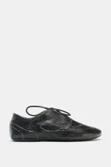 Zapato plano de cuero negro con efecto desgastado y cordones.