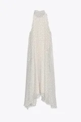 Vestido largo de cuello halter con lazadas ajustables y estampado de lunares negros sobre fondo blanco. Tiene bajo asimétrico, forro interior y cierre con abertura y botón en la espalda.