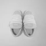 Zapatillas bajas de lona color gris claro, con cordones blancos gruesos y suela de goma blanca. Presentan el logo de la marca en el lateral exterior.