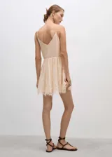 Vestido corto color crema con tirantes finos y escote en V, con detalles de encaje en escote y ruedo.