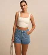 Short de jeans azul claro, corte slim, con trabillas en la cintura, bolsillos delanteros y traseros, y apliques de brillos en los laterales.