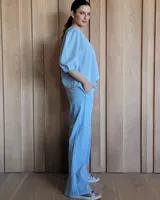 Conjunto de camisa y pantalón de lino blanco. La camisa es de manga larga y se ata en la parte delantera. El pantalón es de corte ancho y tiene cordón en la cintura.
