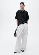 Camisa negra de manga corta confeccionada en mezcla de algodón y lino, con cierre de botones y cuello camisero. Diseño recto y corte holgado.