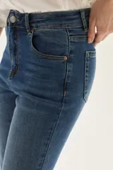 Jean de tiro medio, color azul medio, con silueta ligeramente acampanada desde la rodilla.