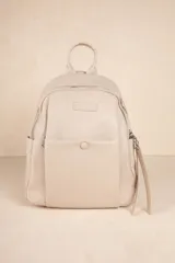 Mochila color beige de cuero sintético, con bolsillo frontal con broche y cierre superior con tiradores largos.