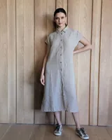 Vestido camisero midi color beige, de lino, con cuello camisero, mangas cortas y abotonadura frontal.