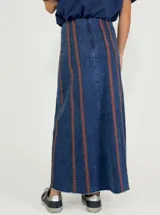 Pollera larga de jean azul con corte acampanado y costuras verticales en color ladrillo.