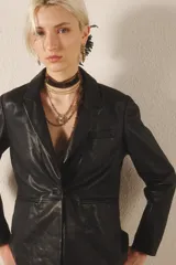 Blazer negro de cuero ovino con proceso de lavado que le da un efecto arrugado. Tiene solapas, bolsillos delanteros y forro interior a tono.