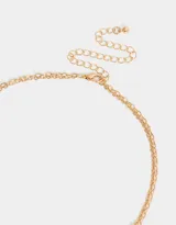 Collar corto multicadena con mostacillas lilas y dije de corazón místico dorado.