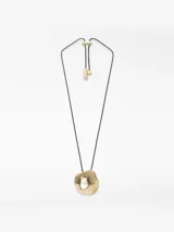 Collar con cordón largo ajustable de poliéster negro. Presenta un dije metálico de forma orgánica con acabado dorado, que contiene un aplique central de resina blanca con apariencia de perla irregular.