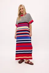 Vestido de tejido de punto color blanco y negro a rayas horizontales, con detalles en rojo y azul en el ruedo y cuello. Presenta cuello redondo con borde rojo y costuras decorativas azules.