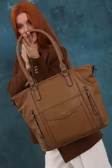 Cartera bandolera de símil cuero color marrón claro, con doble asa rígida y correa regulable. Presenta dos bolsillos frontales con cierre vertical y un bolsillo frontal con solapa y botón. Cuenta con dos divisiones internas.