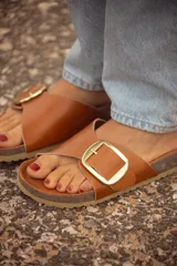 Sandalia marrón de cuero con hebilla dorada, base de corcho y suela beige.