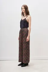 Conjunto de pantalón y kimono con estampado floral en tonos rojos y dorados sobre fondo negro. El pantalón es de corte palazzo y el kimono tiene mangas anchas.