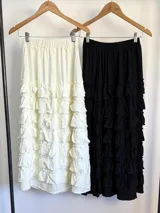 Falda larga negra con cintura elástica y múltiples volados horizontales.