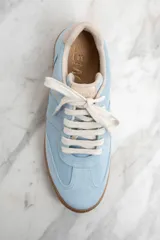 Zapatillas bajas de gamuza celeste con cordones blancos y suela de goma marrón.