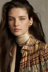 Camisa de mujer confeccionada en ramio 100% con estampado a cuadros en tonos beige, marrón y celeste. Tiene cuello solapa, manga larga con puños, bolsillo de plastrón en el delantero, bajo redondeado y cierre frontal con botones.
