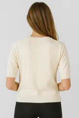 Sweater color crema de tejido de punto, corte ajustado y cuello redondo.