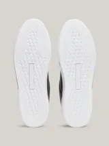 Zapatillas Tommy Hilfiger de cuero azul marino con suela blanca, cordones negros, interior blanco y detalles dorados en el talón y en el lateral.