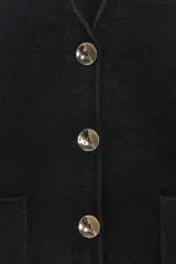Chaleco negro con escote en pico, sin mangas, bolsillos de parche en la parte delantera y cierre frontal con botones dorados.