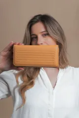 Billetera larga color mostaza de símil cuero con tapa y repartición con cierre. Compartimento con tarjeteros y bolsillos. Compartimento posterior incluye monedero con cierre, tarjeteros y billetes. Bolsillo atrás con cierre.