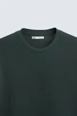 Jersey de punto color marrón oscuro, de corte relajado (relaxed fit), con cuello redondo y manga corta.