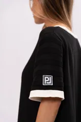 Vestido corto negro de tejido de punto calado, con cuello redondo y mangas cortas con ribete blanco.