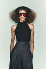 Top negro de cuello halter con cierre de botones en la parte trasera del cuello y espalda descubierta.