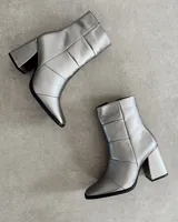 Botín de cuero color marrón con caña media, punta fina y taco geométrico de 10 cm.