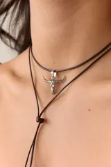 Dije plateado con forma de cráneo de toro con orificio en la frente.