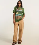 Remera verde militar de algodón con cuello redondo y mangas cortas. Estampado frontal con palmeras, olas y texto "Califa Hour".