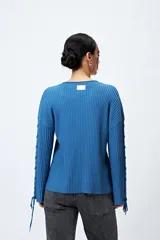 Sweater negro de punto canalé con detalle de trenzado en las mangas y lazo ajustable en el ruedo.