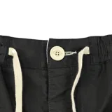 Bermuda de algodón color negro, con cintura elástica y cordón de ajuste color crema. Presenta bolsillos laterales y un pequeño parche con texto en la parte inferior derecha.