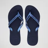 Ojotas Havaianas modelo Elegance, color azul marino oscuro, con tiras delgadas y logo metálico de la marca. La suela es antideslizante y la plantilla ergonómica.