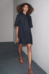 Vestido corto de Zara Woman Collection confeccionado en tejido tipo denim. Tiene cuello solapa, manga corta, bolsillos delanteros ocultos, bajo evasé y cierre frontal con botones.