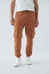 Pantalón cargo color marrón con corte slim, elástico en cintura y cordón ajustable, bolsillos cargo con botones y puños elásticos. Confeccionado en algodón y spandex.