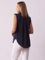 Blusa negra de gasa marca Tahari, con cuello a la base con solapa, abertura central con botones ocultos y detalle plisado en hombros.