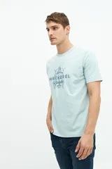 Remera verde agua de manga corta con estampado de dos peces y texto en azul marino.