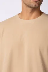 Remera de hombre color crudo, corte oversize, confeccionada en algodón grueso con textura micropanal. Diseño liso sin logos, con costura en forma de 'X' en la espalda. Ideal para un look casual y relajado.