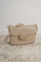 Bandolera color beige con textura símil reptil, cierre con broche metálico dorado y correa larga regulable.