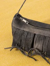 Cartera tipo bandolera color gris oscuro, realizada en cuero ovino, con cierre metálico y forro de poliéster jacquard. Tiene doble bolsillo frontal con cierre imantado y apliques metálicos níquel. Incluye correa corta de cuero para usar al hombro.