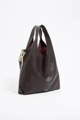 Bolso de mano tipo shopper de cuero color marrón oscuro, con estructura blanda y asa extraíble. Incluye logo metálico de la marca Bimba y Lola, acabados metálicos, bolsillo interior e interior con etiqueta de tejido.